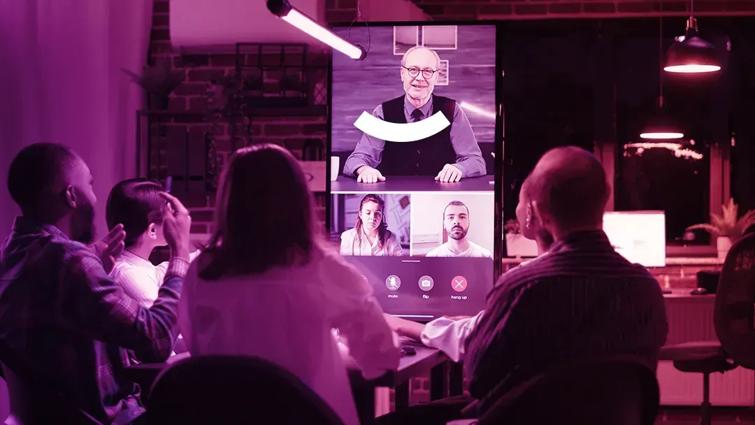 A group of people are sitting around a table having a video conference.