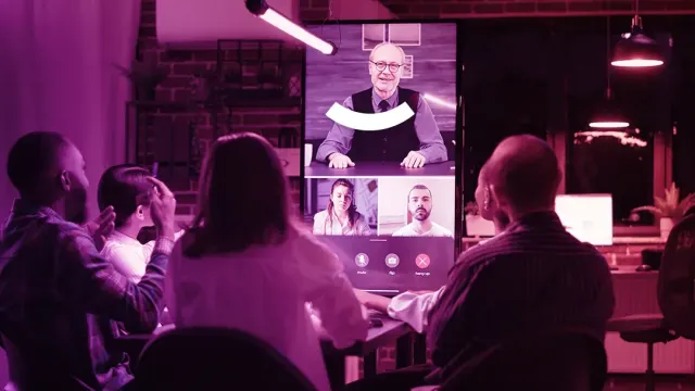 People in a purple-lit room watch a video conference on a large screen.