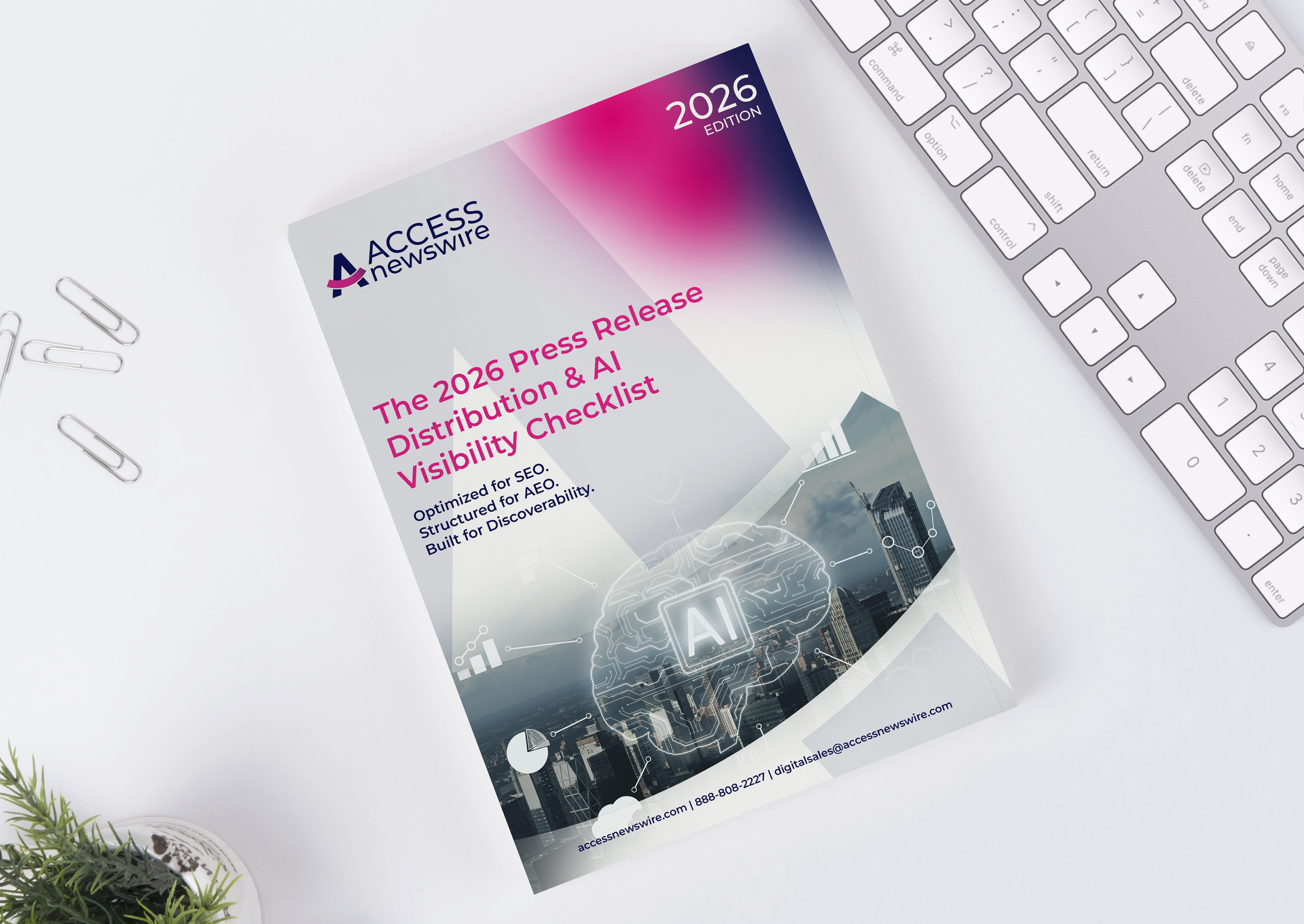 A 2026 press release and AI visibility checklist brochure placed on a white desk next to a keyboard and a small plant.