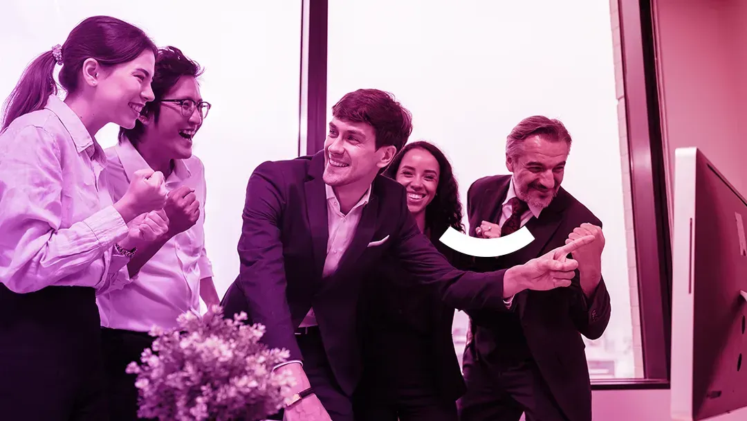 Group of people smiling and clapping indoors, celebrating in a pink-lit room.