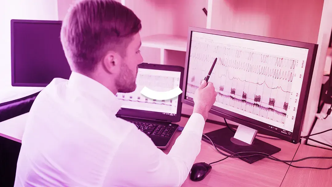 A man is sitting at a desk looking at a computer screen.