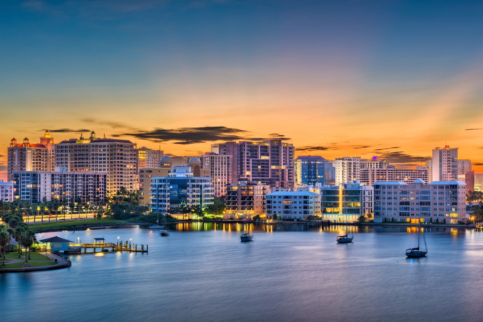 A city skyline overlooking a body of water at sunset.