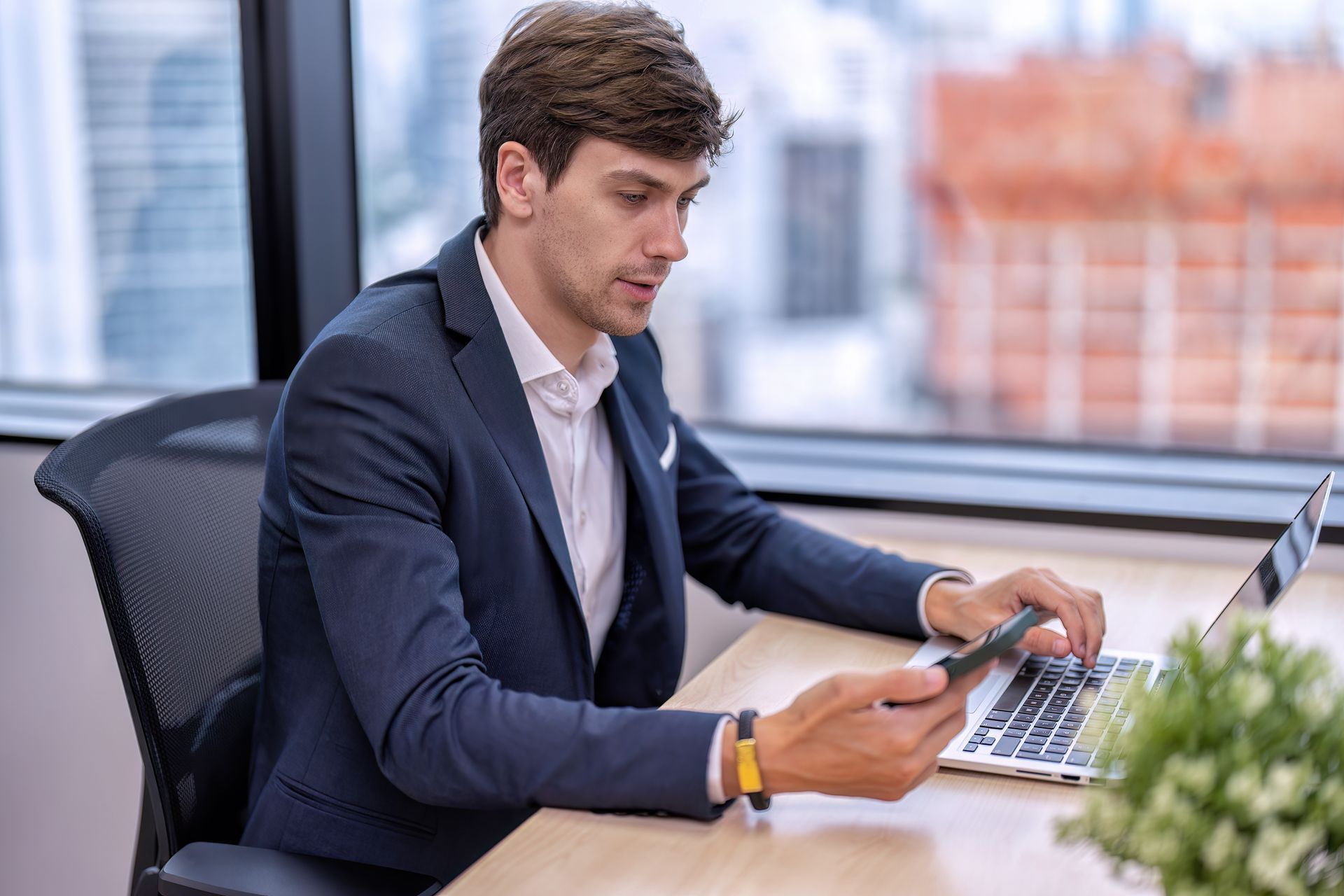 Two people are shaking hands in front of a computer screen.