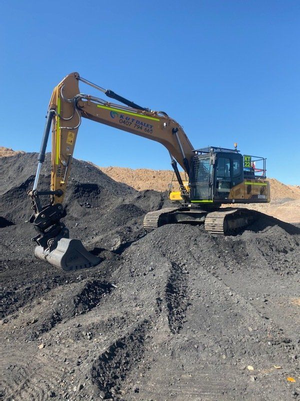 Digger in dark dirt with logo on — Earthmoving Near Me in Australia