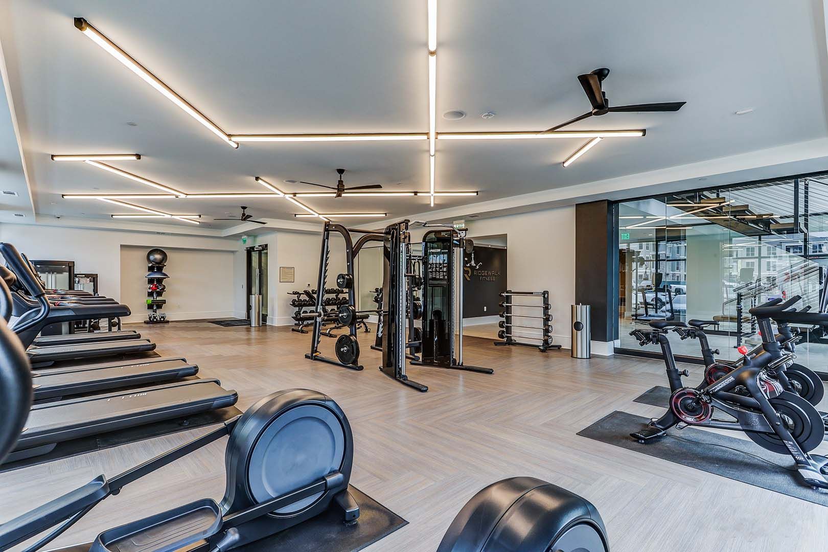 A large gym with a lot of equipment and a ceiling fan.