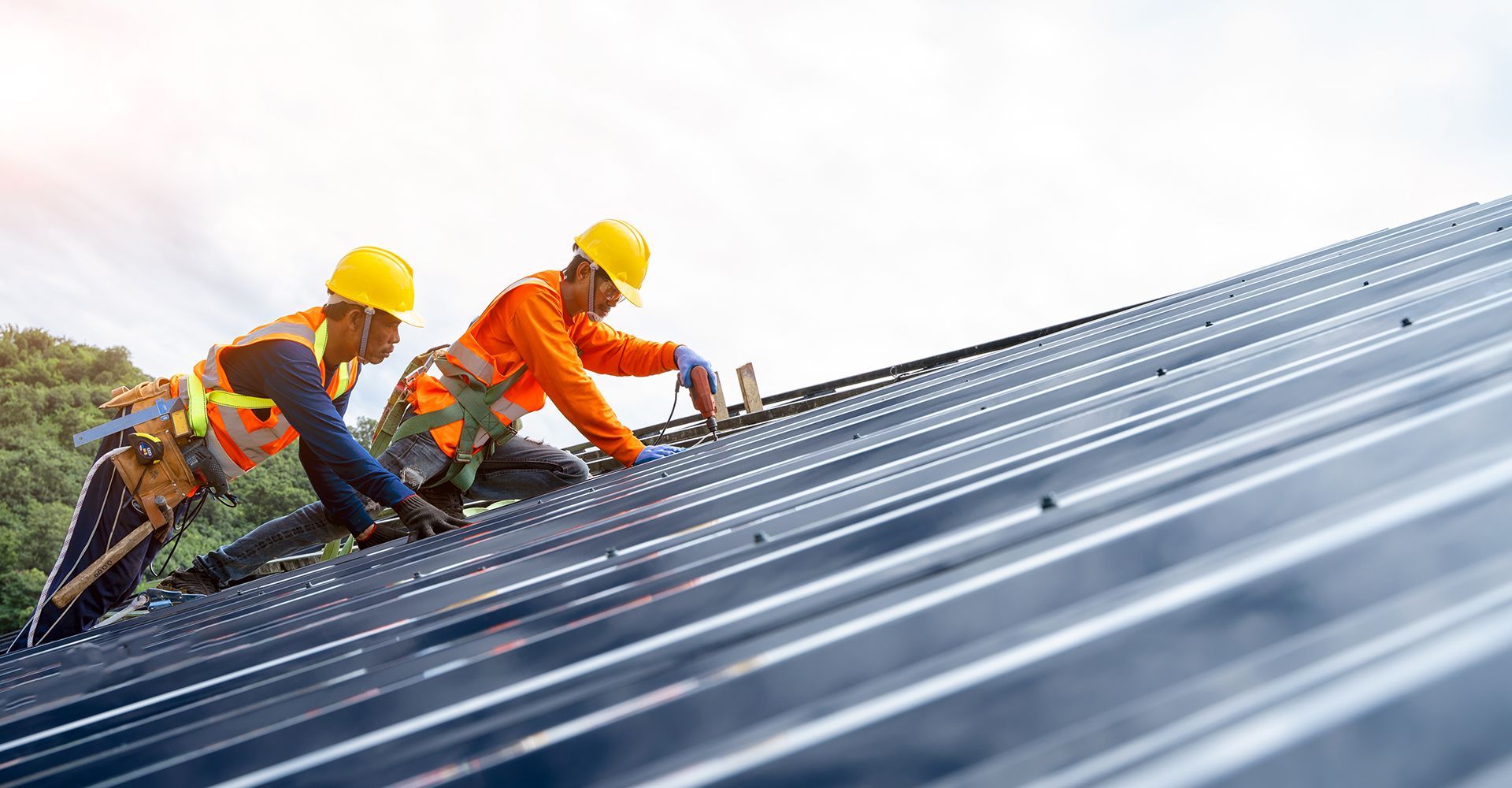 Two construction workers are working on the roof of a building.