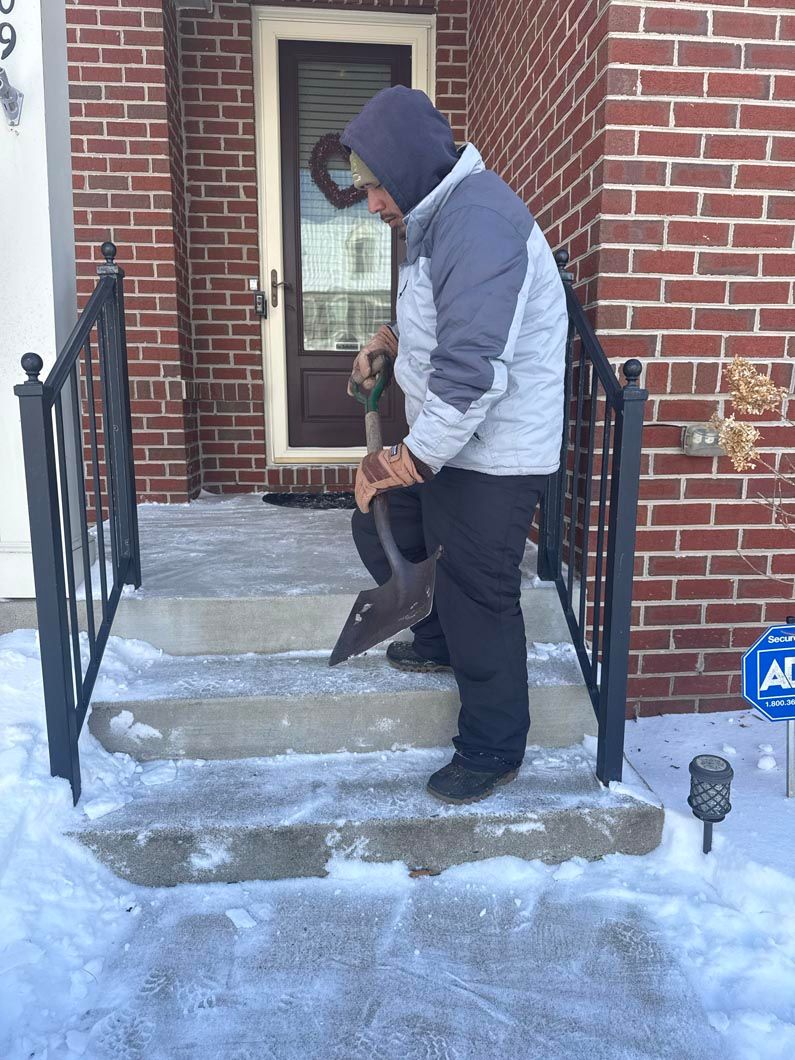 Person clearing snow on brick front steps outside a house
