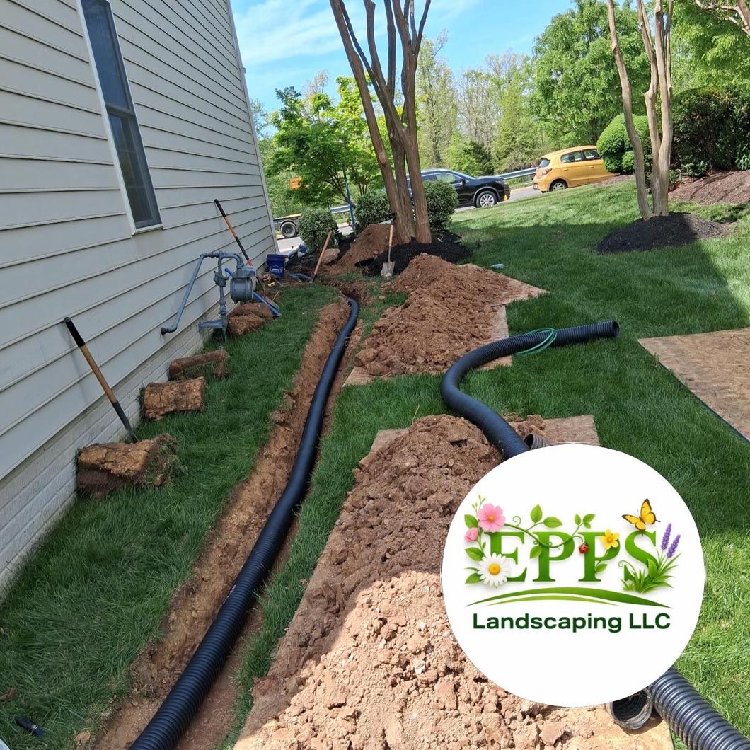 Landscaping work with black drainage pipes, dirt trenches, and mulch beside a house in a yard