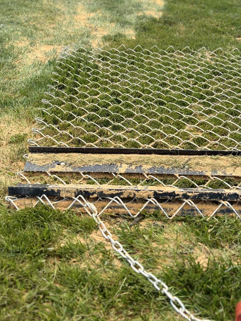 Metal mesh mat and chain laid on grass, showing a temporary ground covering or barrier