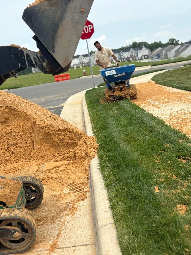 Construction debris on a residential street with a blue wheelbarrow and piles of mulch by the curb.
