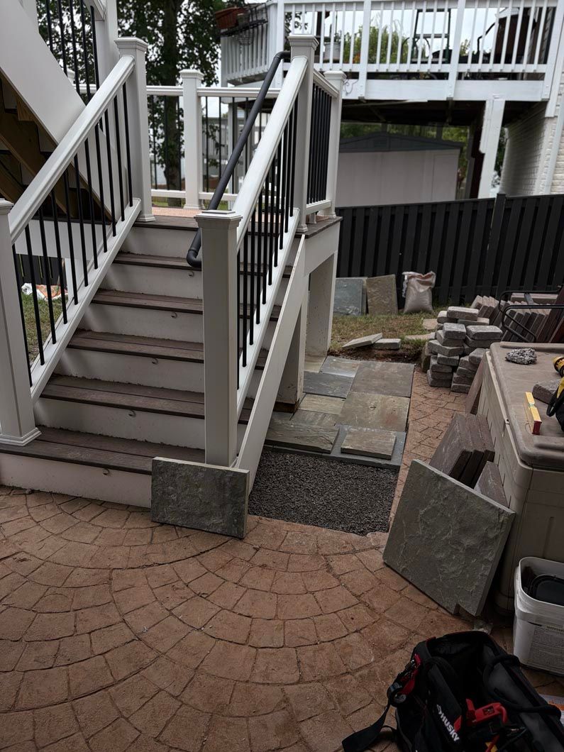 Outdoor stairway beside a patio with stacked cinder blocks and construction materials