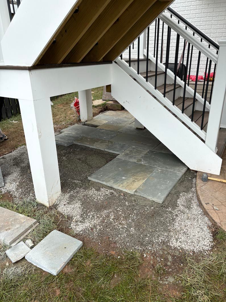 Outdoor stairway over gravel with concrete stepping stones and a white support column.