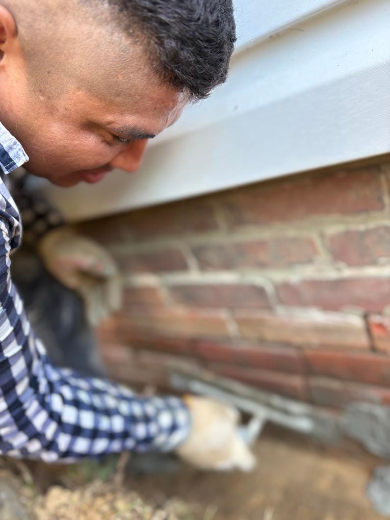 Person inspecting a brick wall crack near the foundation with a gloved hand