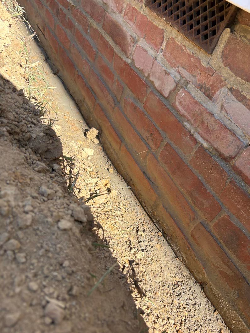 Brick wall beside dirt trench and concrete footing construction detail