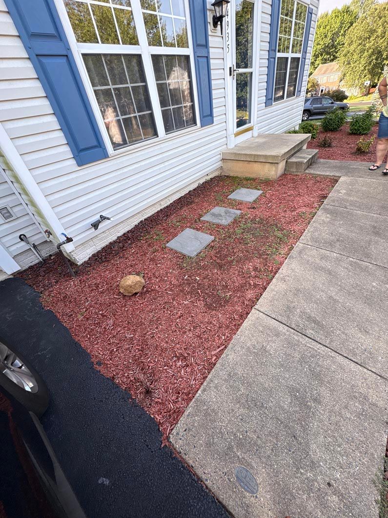 Front walkway with white house siding, blue shutters, red mulch, stepping stones, and a concrete path