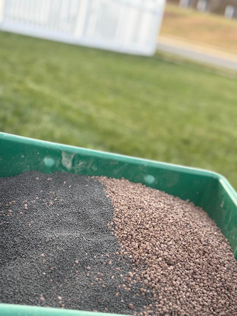 Close-up of black and tan granular material in a green plastic container outdoors