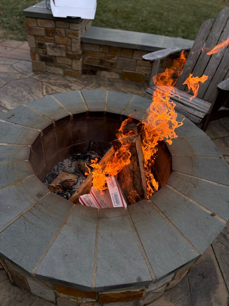 Stone fire pit with bright flames burning outdoors on a patio