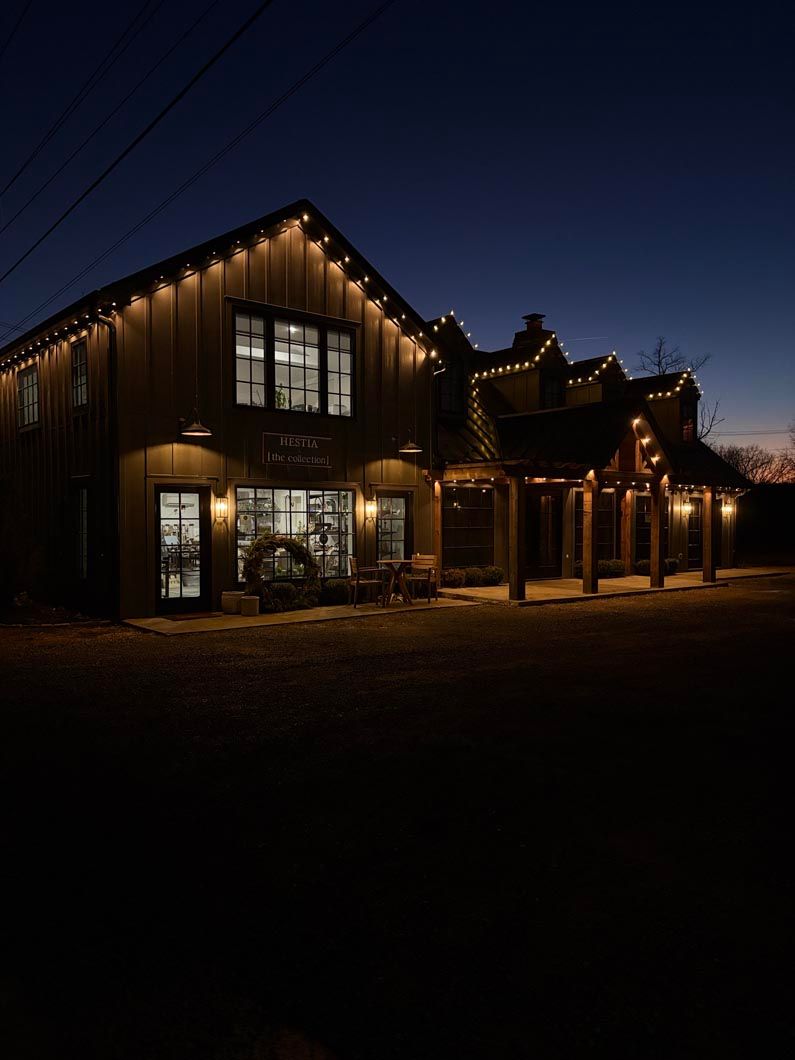 Cabin-style house glowing with warm string lights at dusk, set against a dark blue sky.