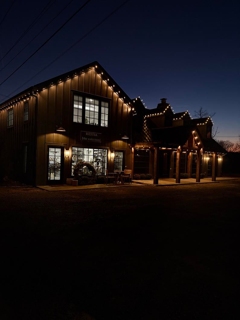 Warmly lit wooden house at night with string lights and large windows under a dark sky