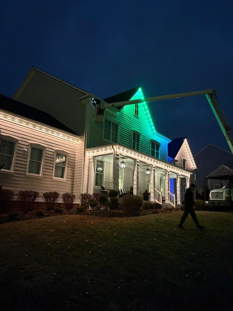 House lit with green and white lights at night, with a person walking on the lawn