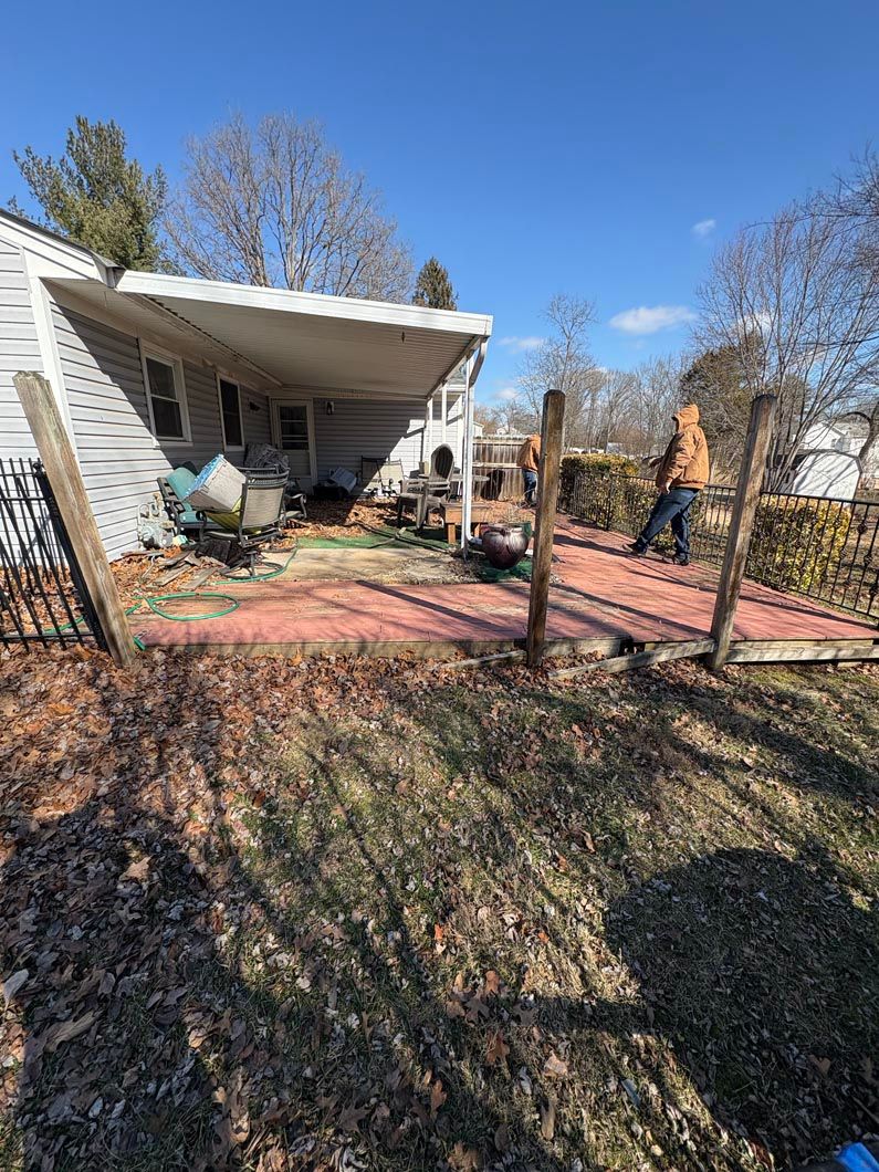 Backyard patio with a white canopy, red brick paving, and leafless trees under a blue sky