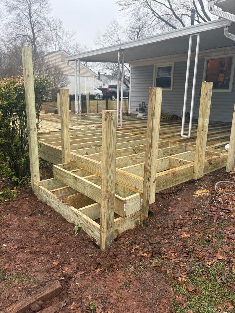 Wooden ramp and railings under construction beside a house on a wet, leaf-covered yard
