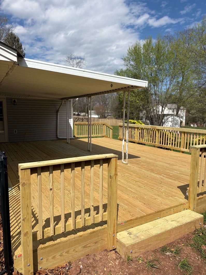 Wooden deck with railing and awning beside a house on a sunny day