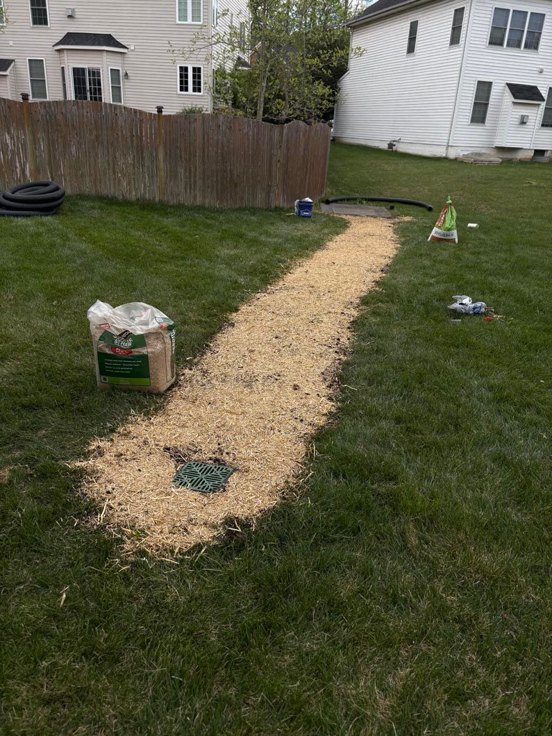 Gravel path through a backyard lawn toward a white tent, with a sandbox in the foreground.