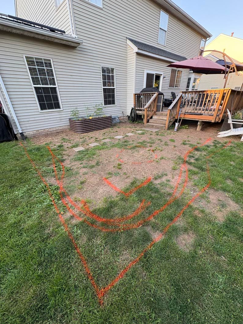 Backyard patio with chair, umbrella, and red chalk heart drawn on grass near a house