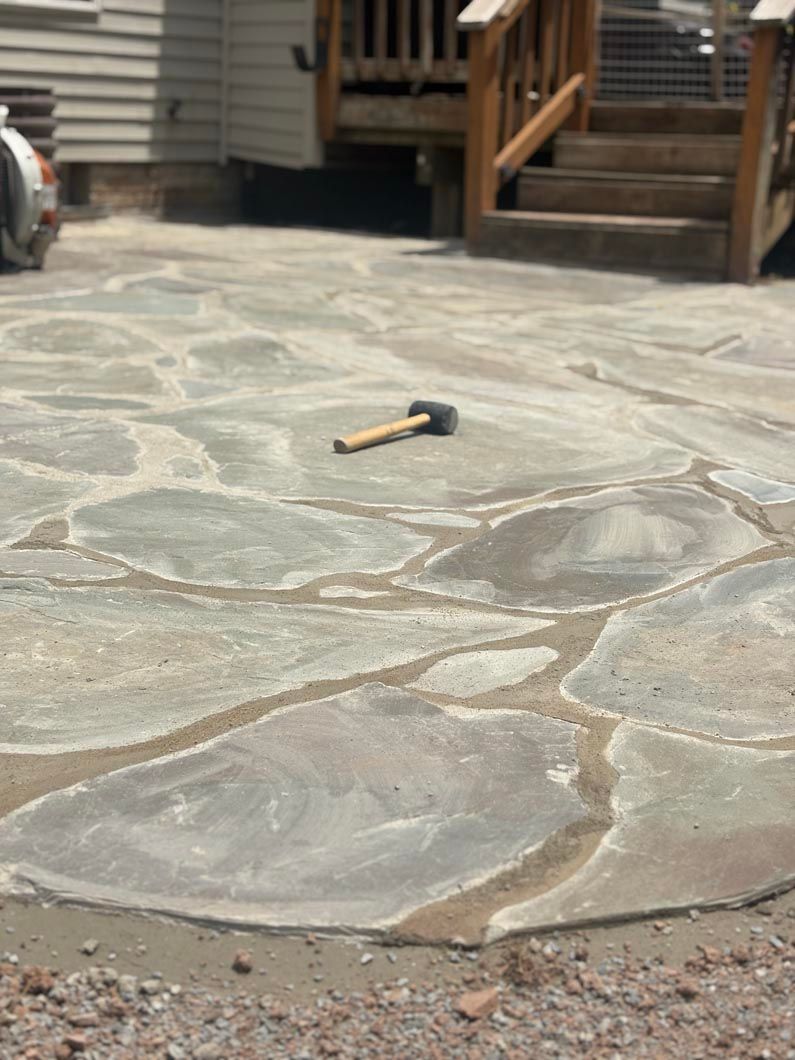 Hammer on a stone patio in front of a wooden house steps