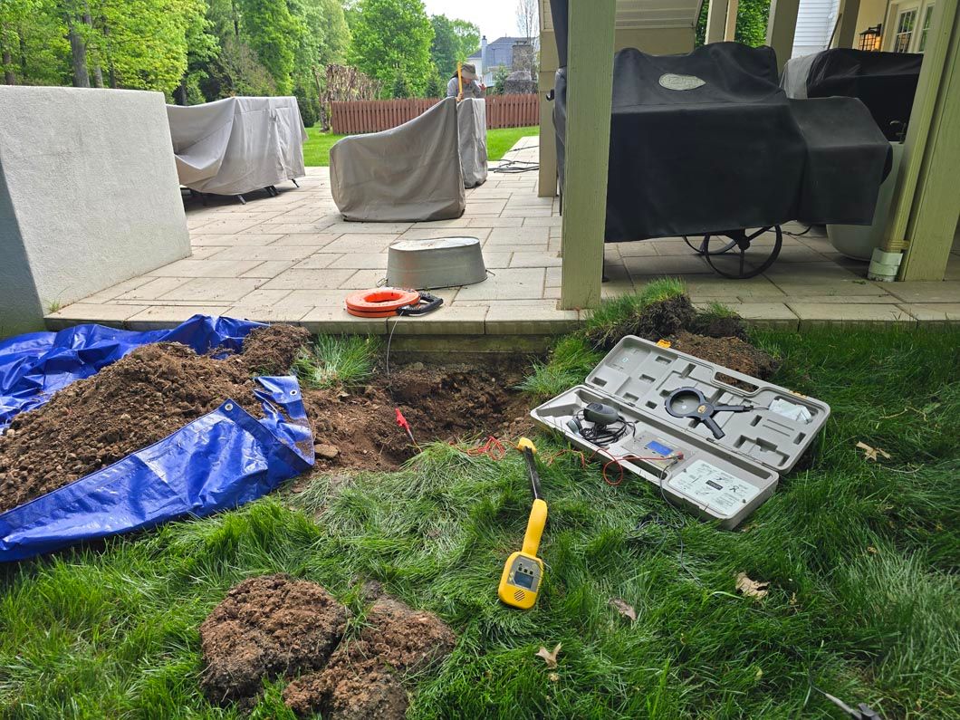 Backyard garden work area with soil, a blue tarp, tools, and a patio in the background