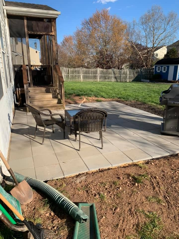 Backyard patio with chairs and fire pit beside a wooden deck and fenced lawn