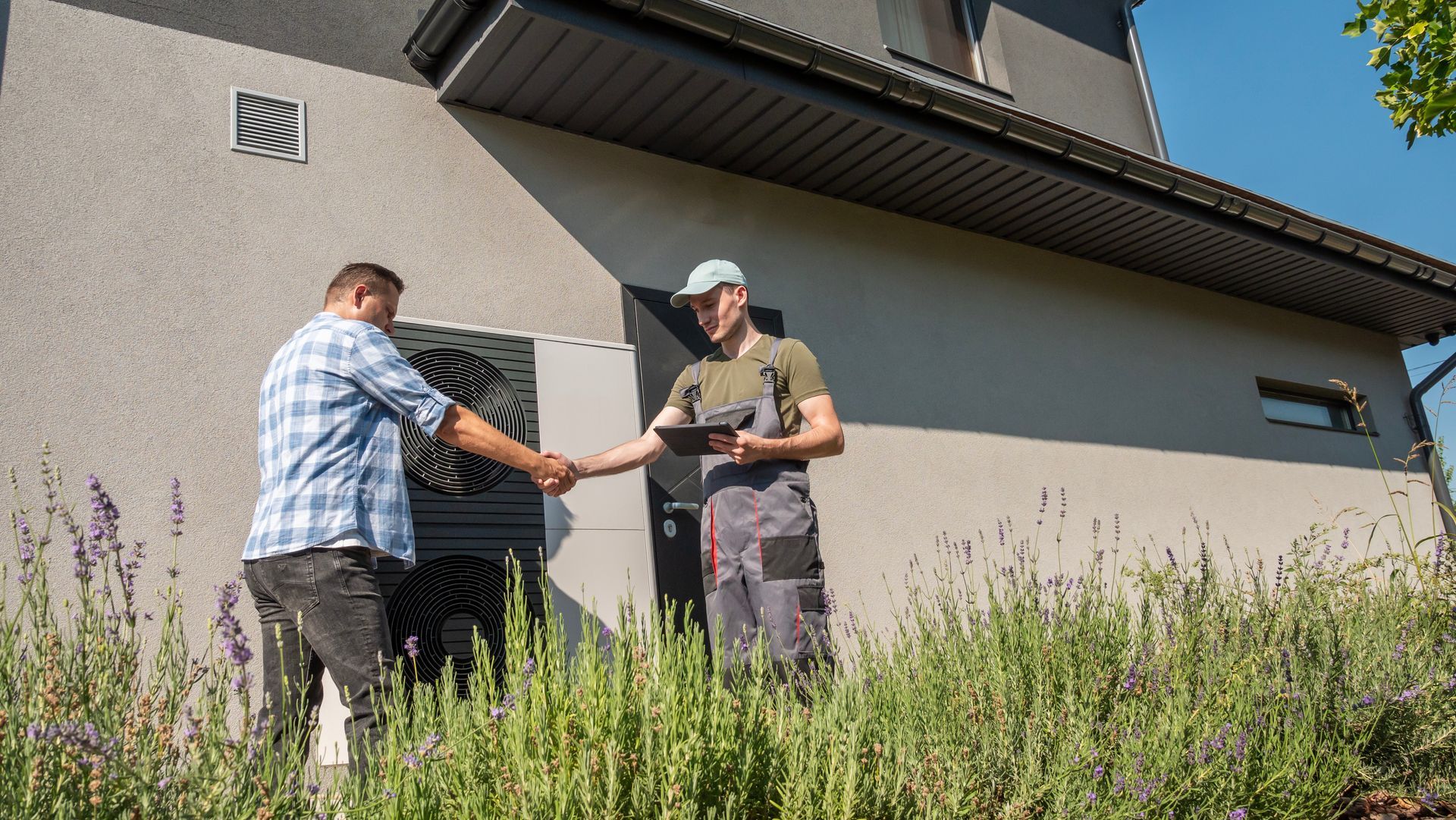 Deux hommes se serrent la main devant une maison.