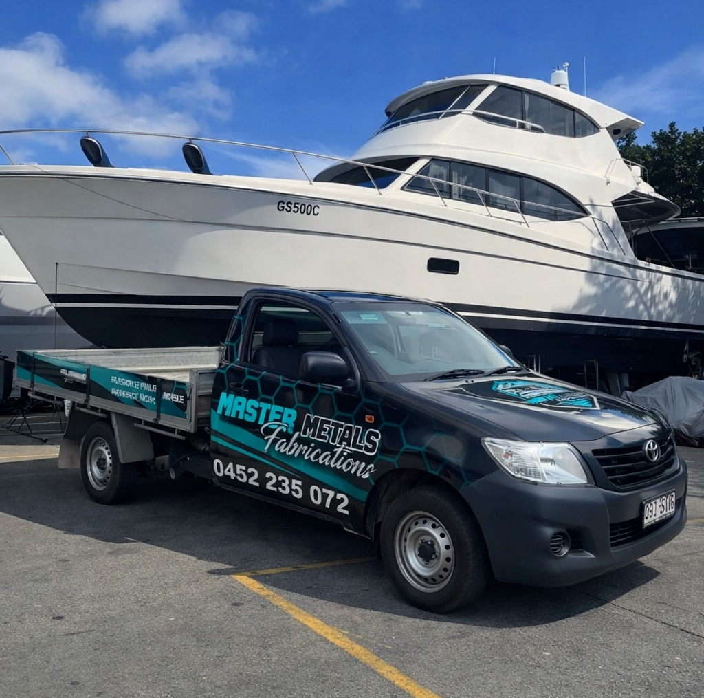 Black pickup truck with business logo parked in front of a large yacht, sunny day — Master Metals Fabrication in Labrador, QLD
