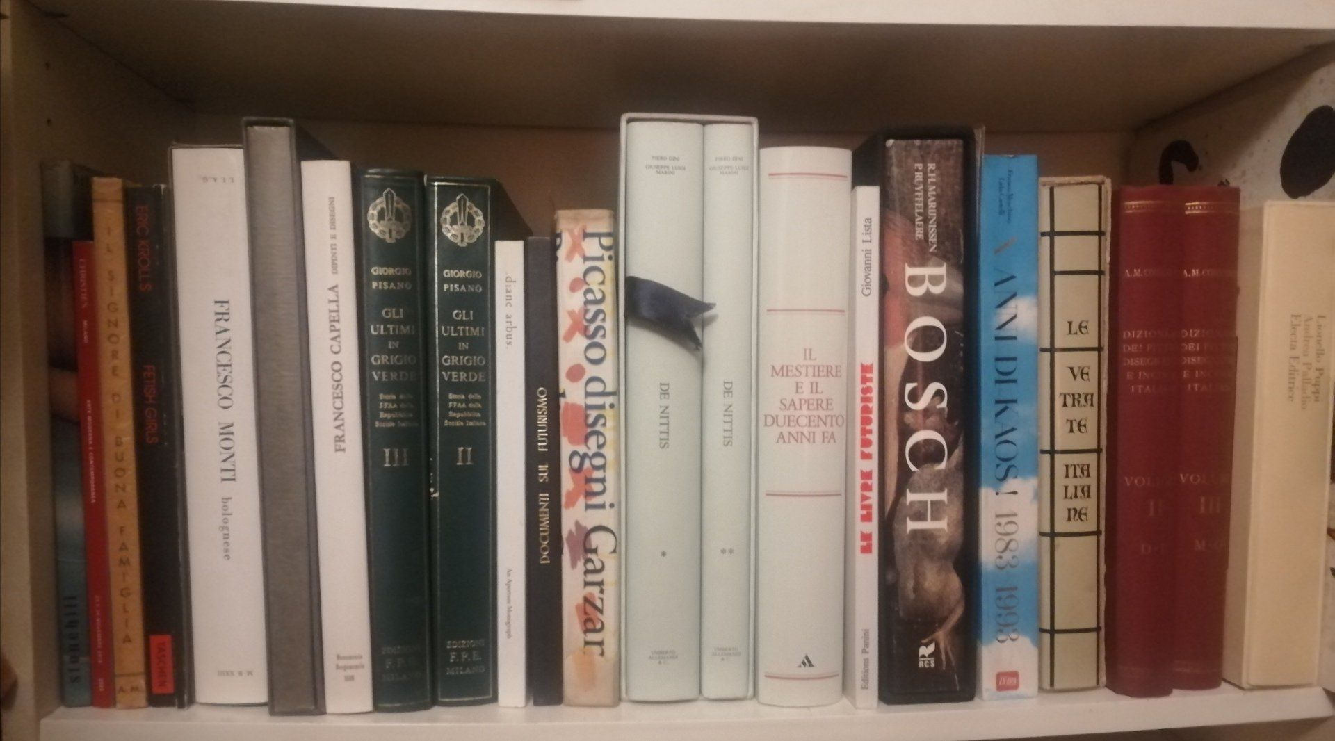Books of varying colors neatly arranged on a shelf inside a cardboard box.