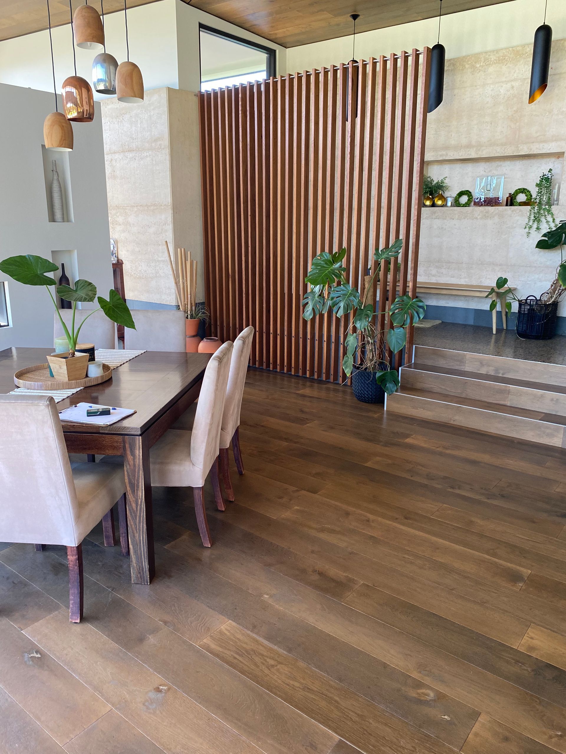 Dining Area With Wooden Floors, Table, Chairs, and Vertical Wood Panel Wall. Plants and Neutral Tones — My Timber Flooring Blinds & Shutters in Erina, NSW