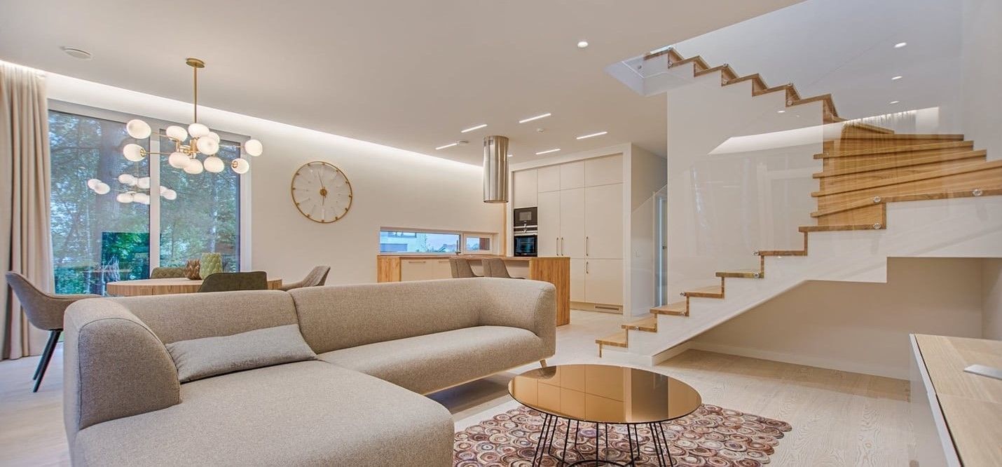 Modern Living Room With a Beige Sectional, Wooden Stairs, and Round Coffee Table — My Timber Flooring Blinds & Shutters in Erina, NSW