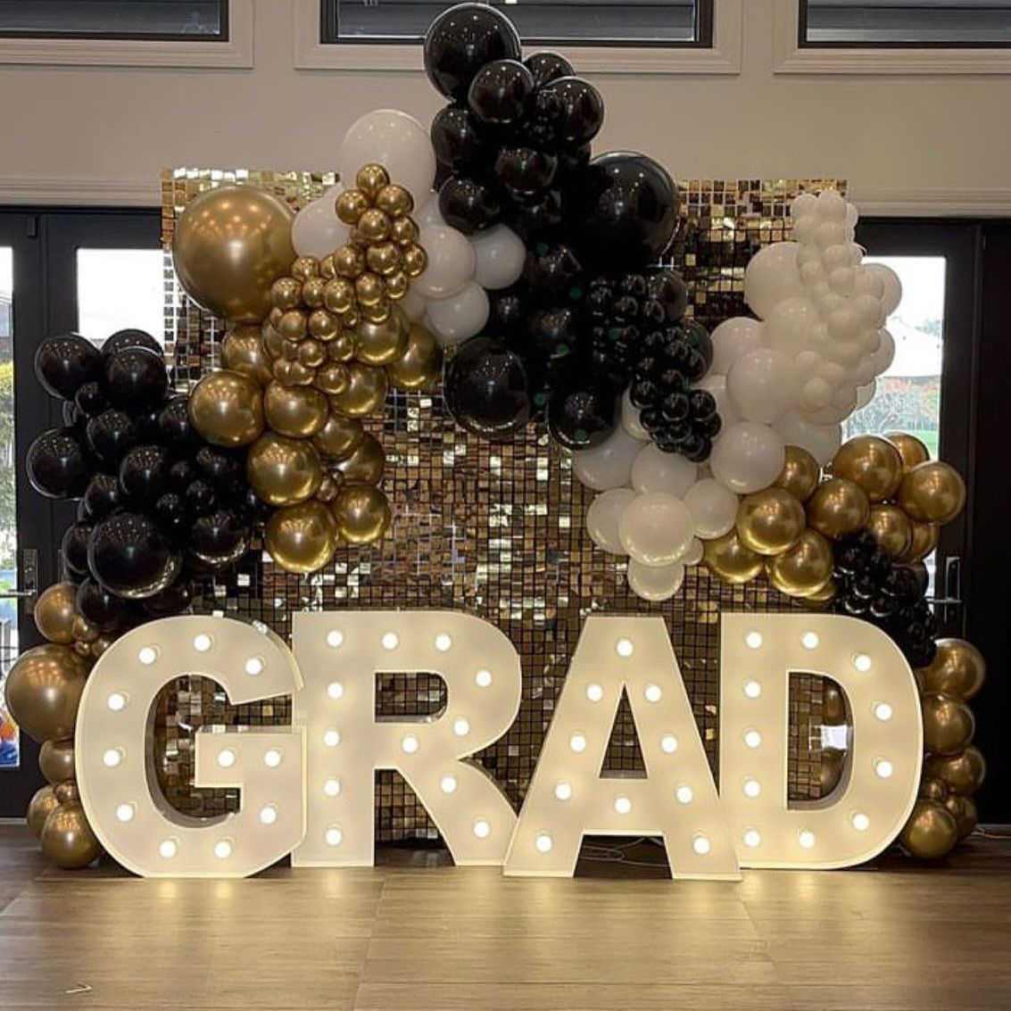Graduation party backdrop: gold, black and white balloons with illuminated