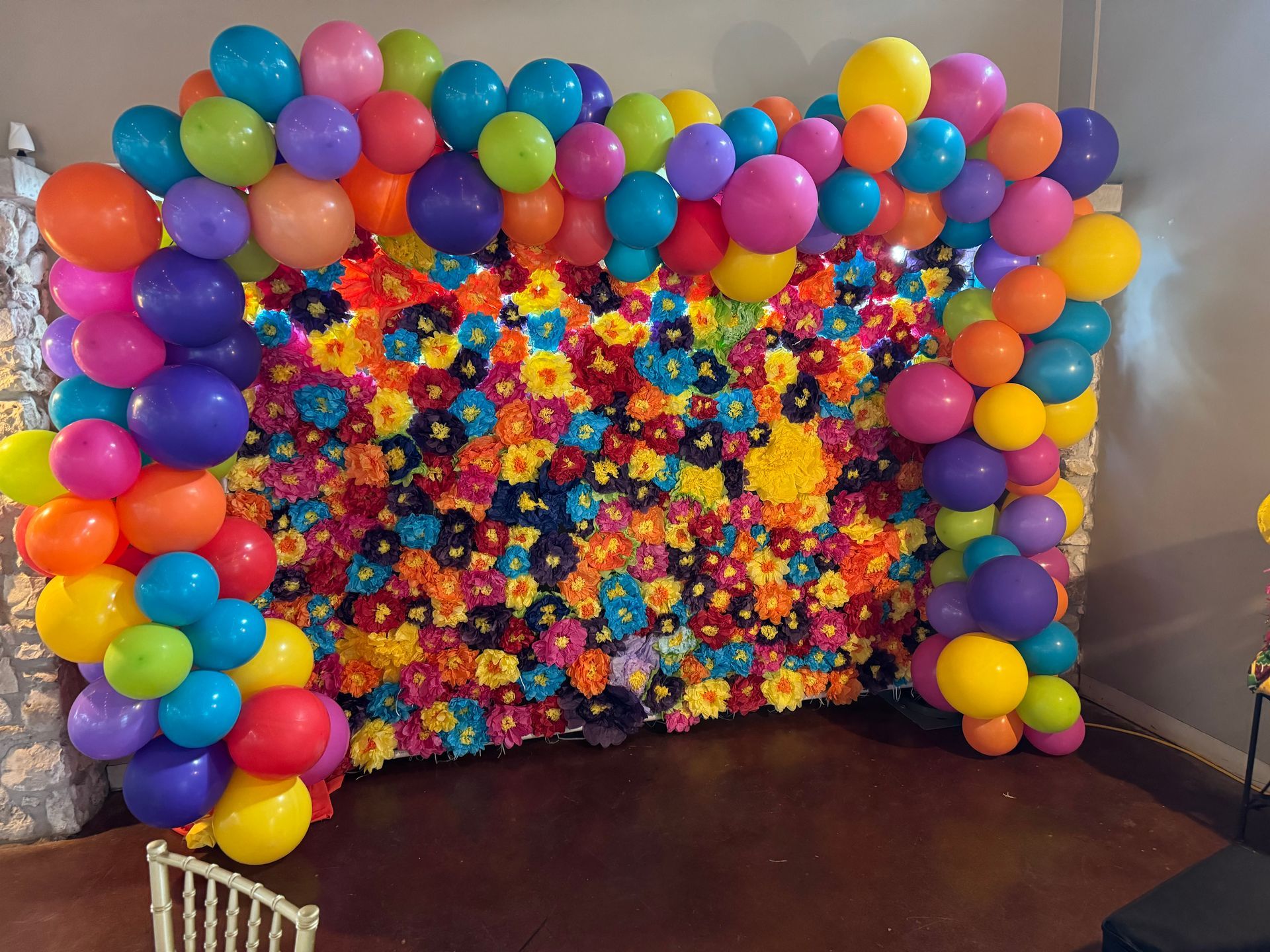 A colorful backdrop with balloons and flowers, creating a vibrant party or event setting.