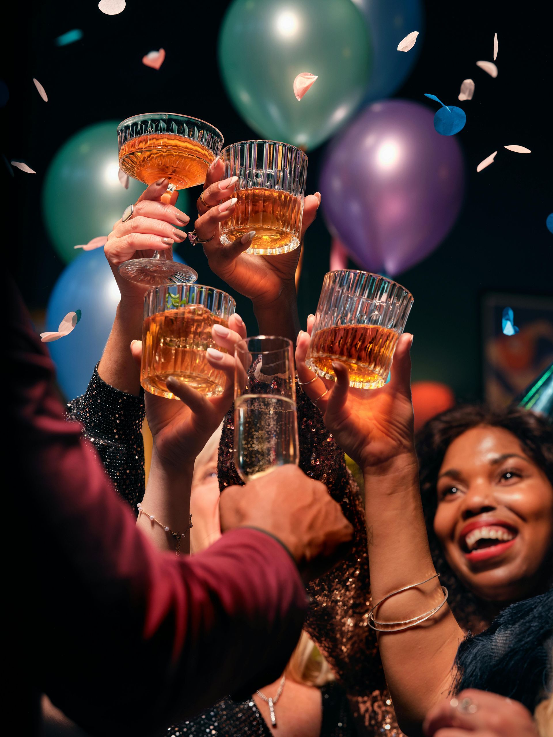 People toasting drinks at a party with balloons in the background.