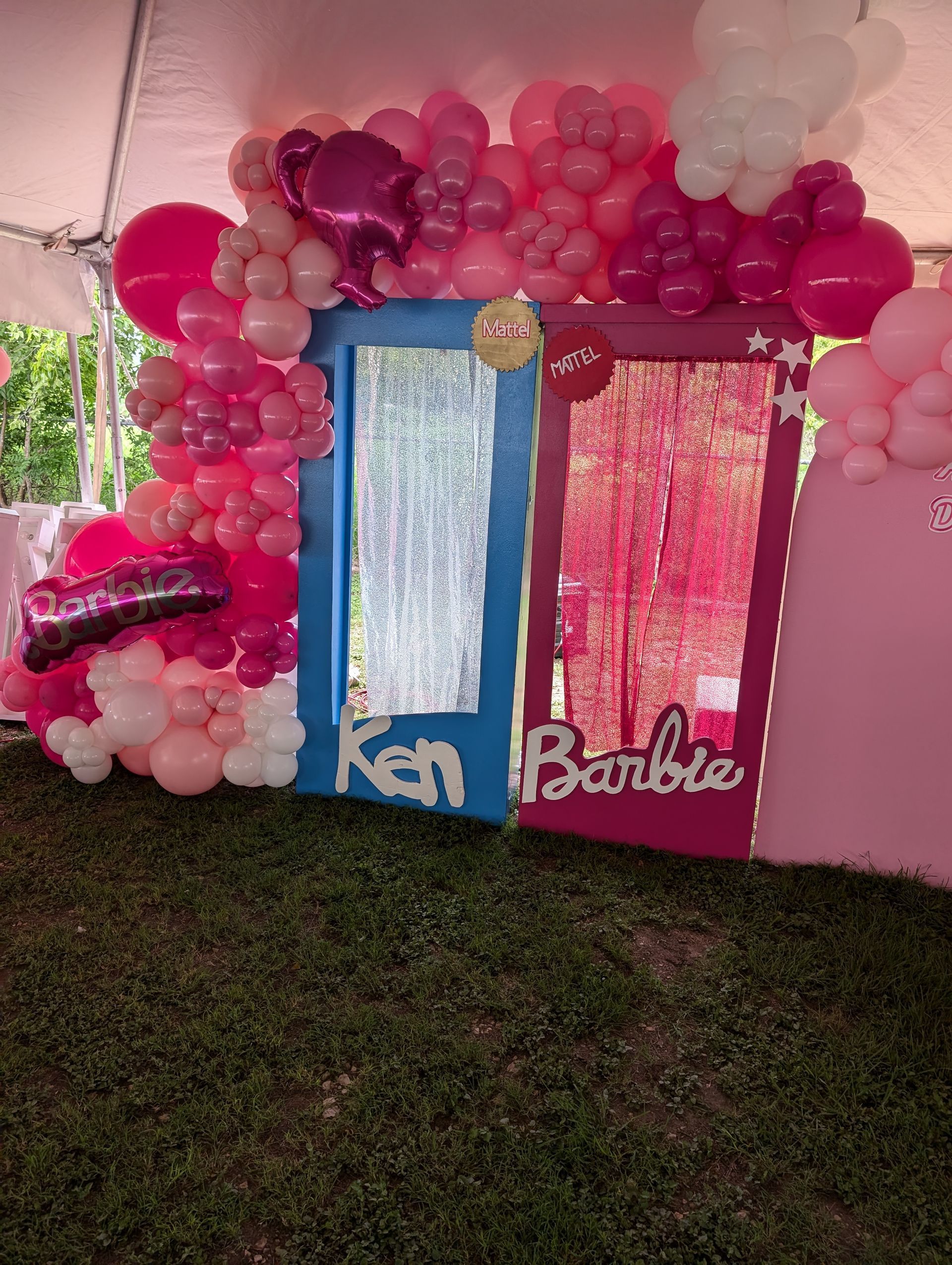 Barbie-themed party setup with pink, blue, and white balloons, Ken and Barbie door cutouts with glitter curtains.