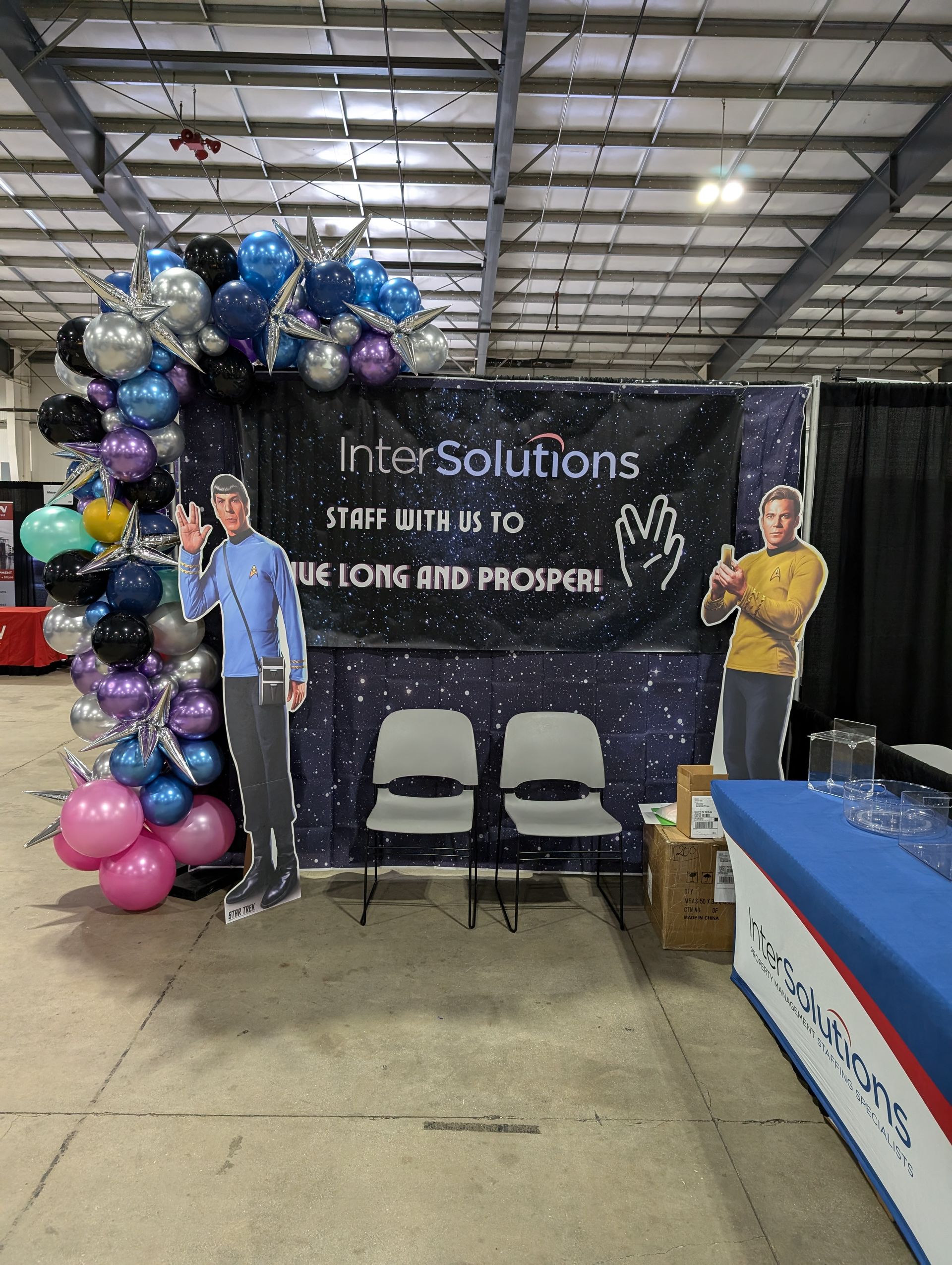 Booth with balloons, cutouts of people giving the Vulcan salute, and a sign that says