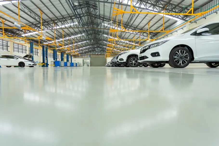 A bright, spacious car service workshop with white cars parked on a smooth, reflective floor.