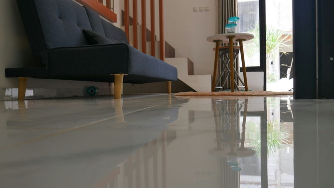 Low-angle shot of a gray sofa and a small round table on a reflective, polished light-colored tile floor.