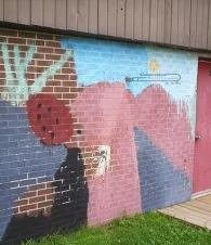 Colorful mural on a brick wall showing a red-haired figure against pink and blue mountain-like shapes.