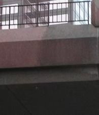 A building balcony with black metal railings above a dark overhang.