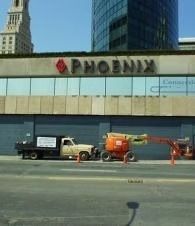 Street view of a PHOENIX building with parked trucks and a construction lift in front