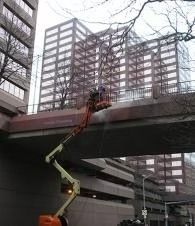 Cherry picker lifting a worker to a bridge girder in a city construction site
