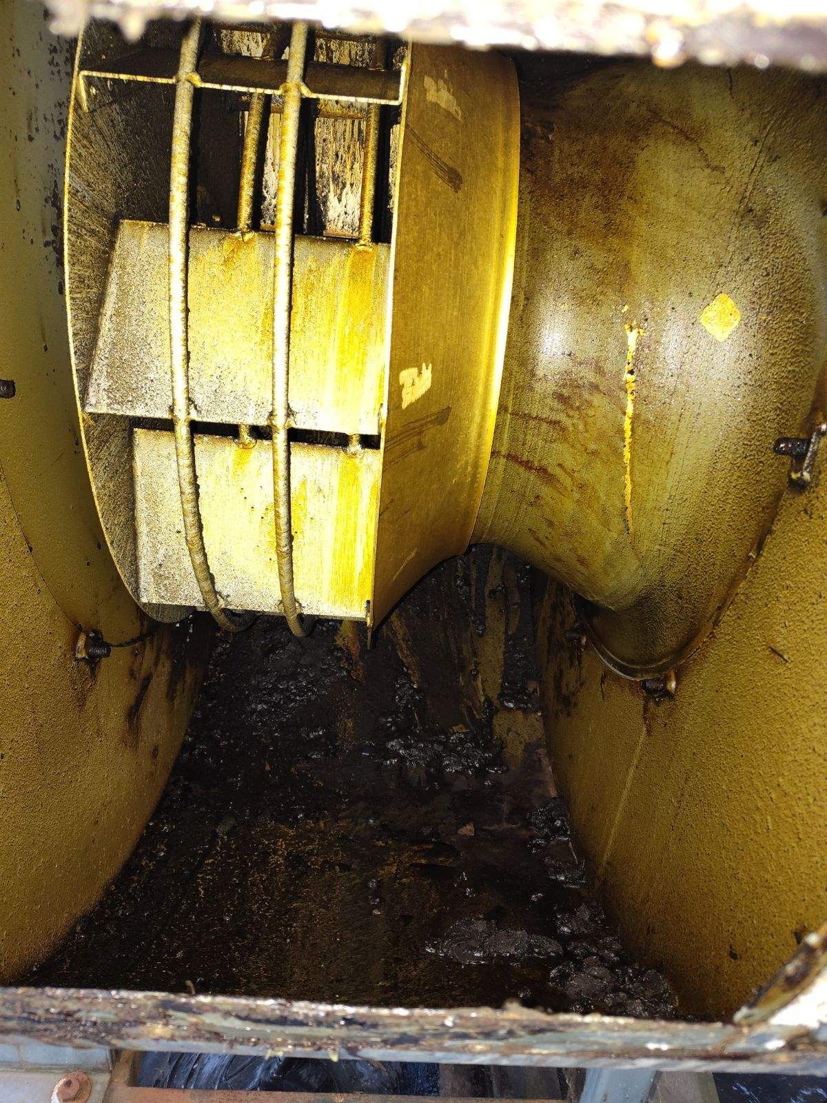 Yellow industrial duct with a dirty fan and dark debris inside; close-up interior view