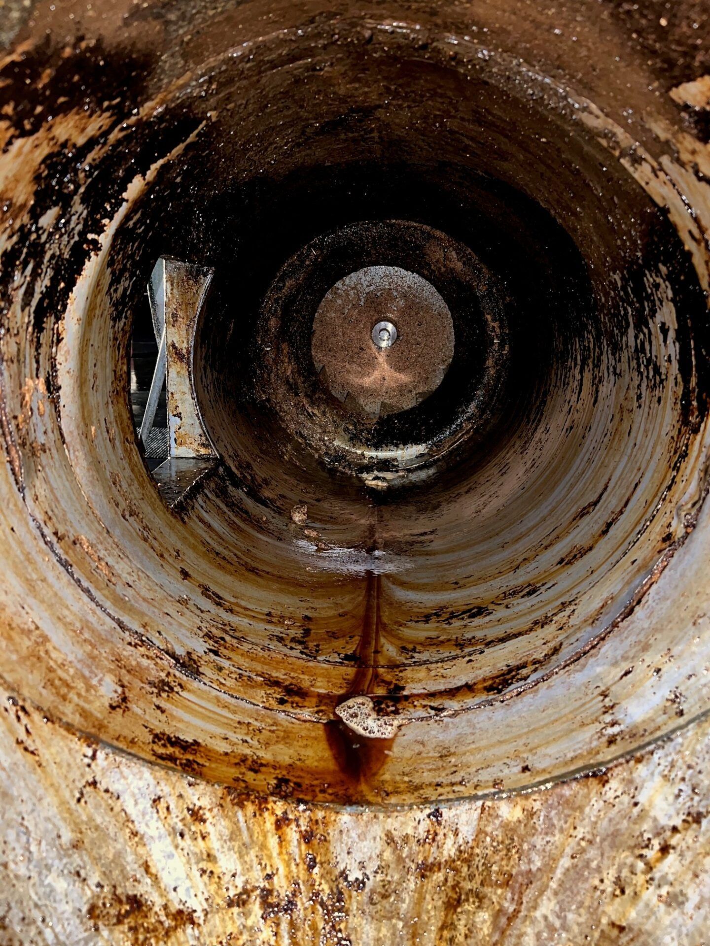 Rusty inside view of a large metal pipe with concentric rings and a central opening